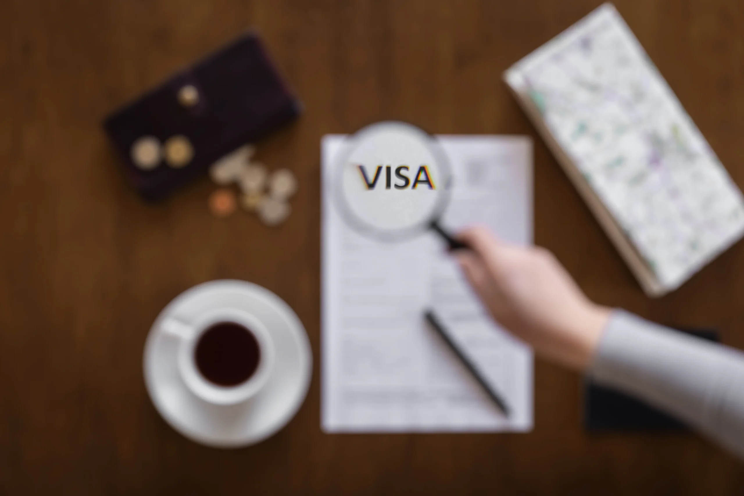Dokument sa oznakom VISA i lupa na stolu – priprema zahteva za vizu i boravišnu dozvolu u Srbiji